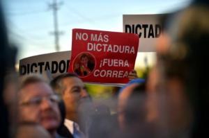 Activistas opositores protestan contra la reforma constitucional que prevé la reelección indefinida desde 2021 en Ecuador con pancartas que rezan "No más dictadura", "Fuera Correa", el 3 de diciembre de 2015 en Quito (AFP | RODRIGO BUENDIA)